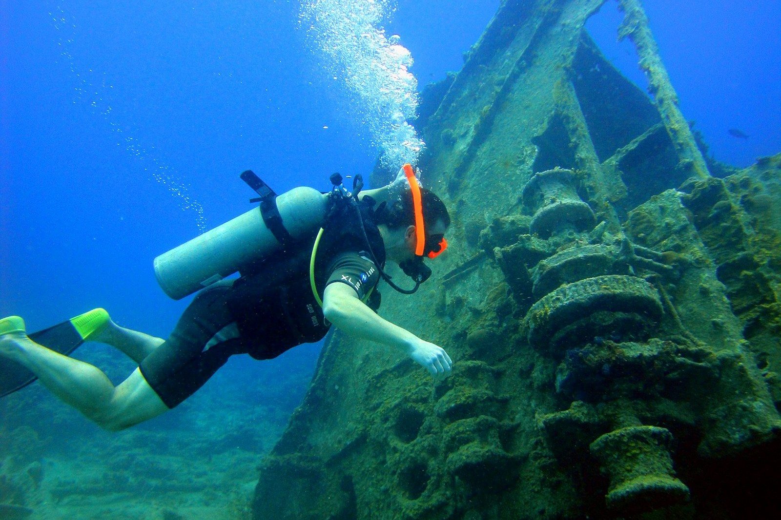 a person in a scuba suit diving next to a ship